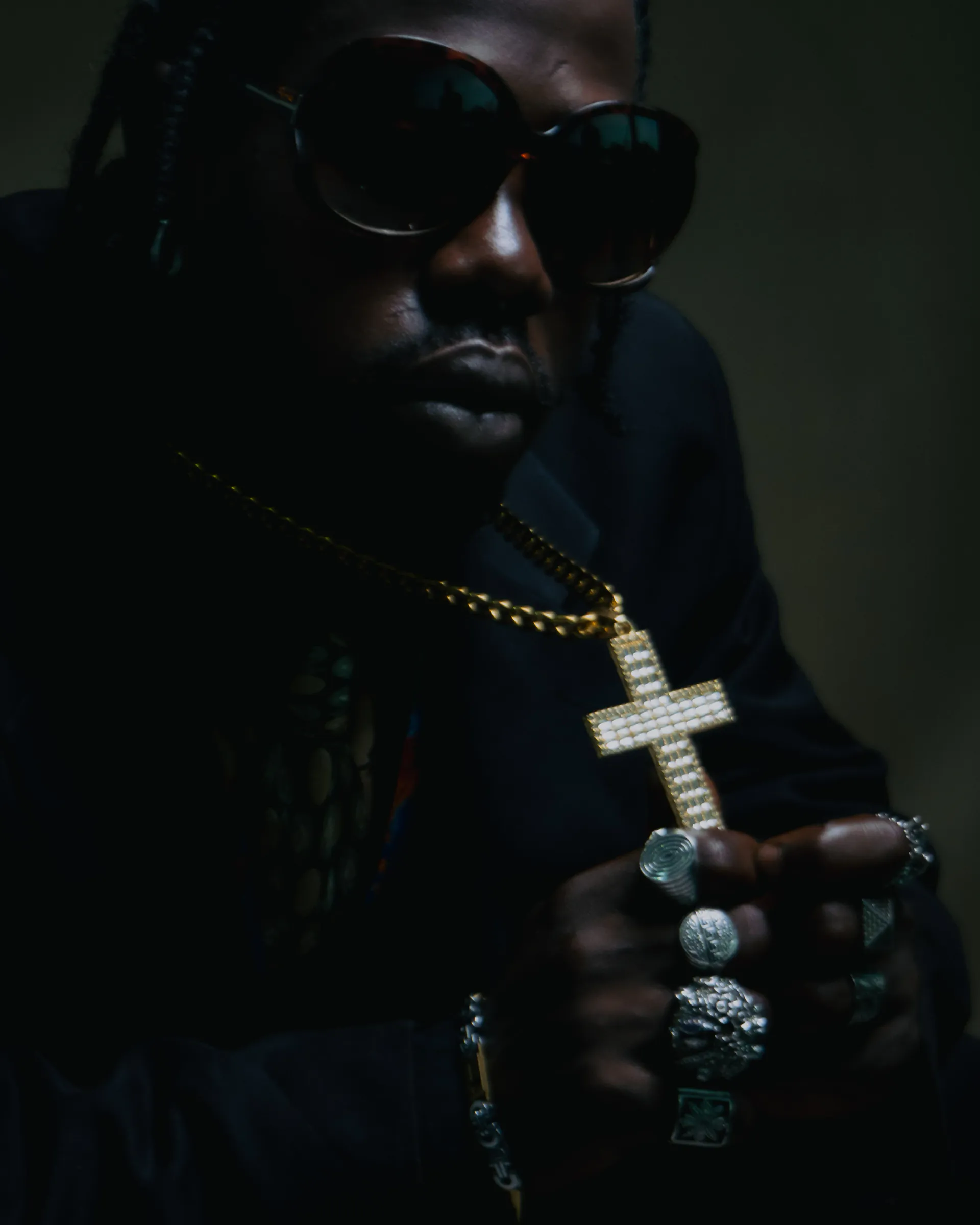 Artist wearing sunglasses and holding a microphone in the “DESIGNER” release visuals